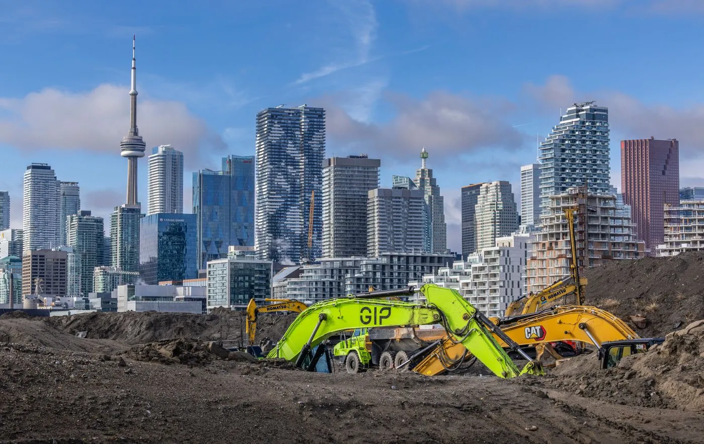 Excavators on a Toronto construction site with the CN Tower and skyline behind